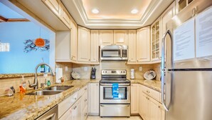 A modern kitchen with granite countertops, stainless steel appliances, and light wood cabinetry. - Gulf views w/scenic elevated sundeck, heated shared pool, boat dock availability (Marathon)