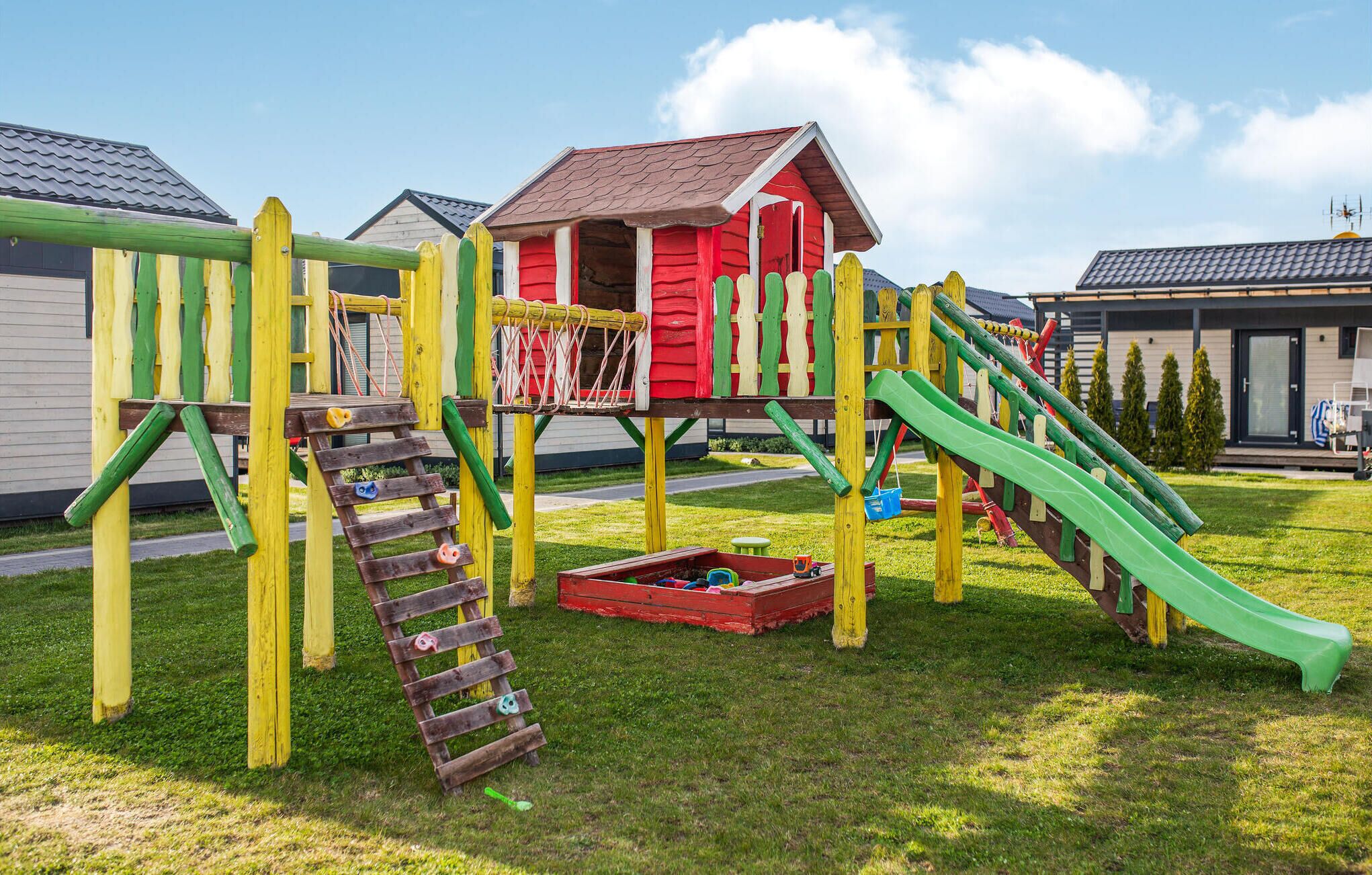 Un patio de recreo con una casita roja, toboganes y estructuras para escalar.