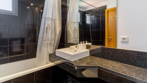 A modern bathroom with a bathtub, a sink, and a shower. - Jardins do Oceano (Santa Cruz)