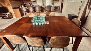 Un comedor con una mesa de madera, seis sillas y un recipiente de vidrio sobre la mesa.