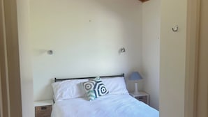 A bedroom with a bed, a nightstand, a lamp, a ceiling fan, and a wooden ceiling. - River Front Cabin (Bridgewater on Loddon)