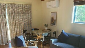 A cozy living room with a wooden ceiling, a round glass table, a grey sofa, and a white rug. - River Front Cabin (Bridgewater on Loddon)