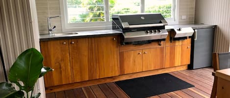 Une cuisine compacte dotée d’une cuisinière à gaz intégrée, de meubles en bois et d’une fenêtre donnant sur un espace verdoyant.