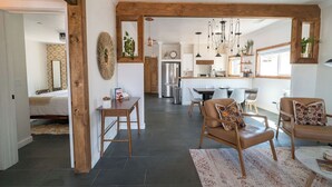 Un vaste espace de vie agrémenté d’un encadrement de porte en bois, d’une table à manger avec des chaises, et d’une cuisine en arrière-plan.