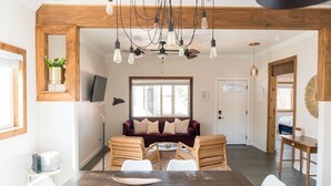 Un coin repas avec une table et des chaises en bois, un canapé avec des coussins et un luminaire au plafond.