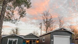 Un bâtiment à deux étages avec un garage, une véranda couverte avec des chaises et une allée gravillonnée.