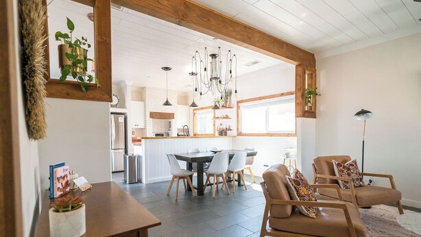 Un salon spacieux avec un coin repas, des poutres apparentes et un décor moderne.