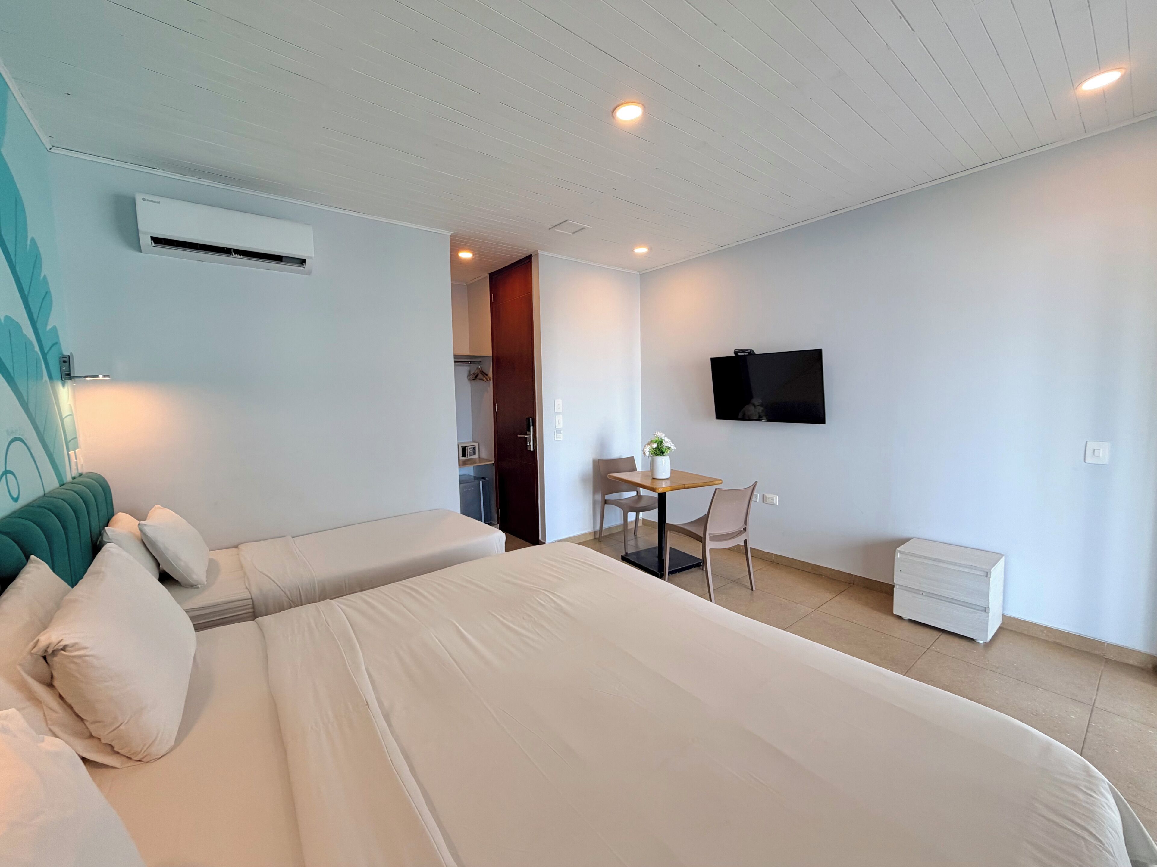 Une chambre d’hôtel comprenant un lit, un bureau avec une chaise, un téléviseur fixé au mur et un appareil de climatisation.