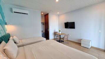 Une chambre d’hôtel comprenant un lit, un bureau avec une chaise, un téléviseur fixé au mur et un appareil de climatisation.