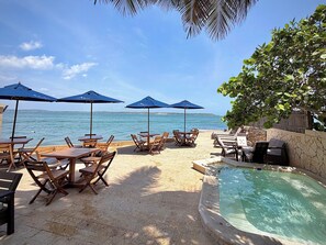 A beachside patio with wooden tables and blue umbrellas, a pool, and a view of the sea. - Hotel Caribbean Cartagena (Cartagena)