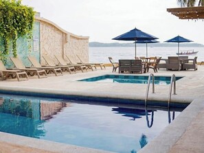 A poolside area with lounge chairs, umbrellas, and a view of the sea. - Hotel Caribbean Cartagena (Cartagena)