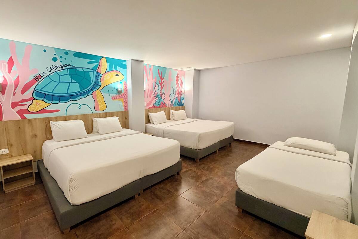 Ein Hotelzimmer mit drei Betten, einem Wandbild einer Schildkröte und einem Holzkopfteil.