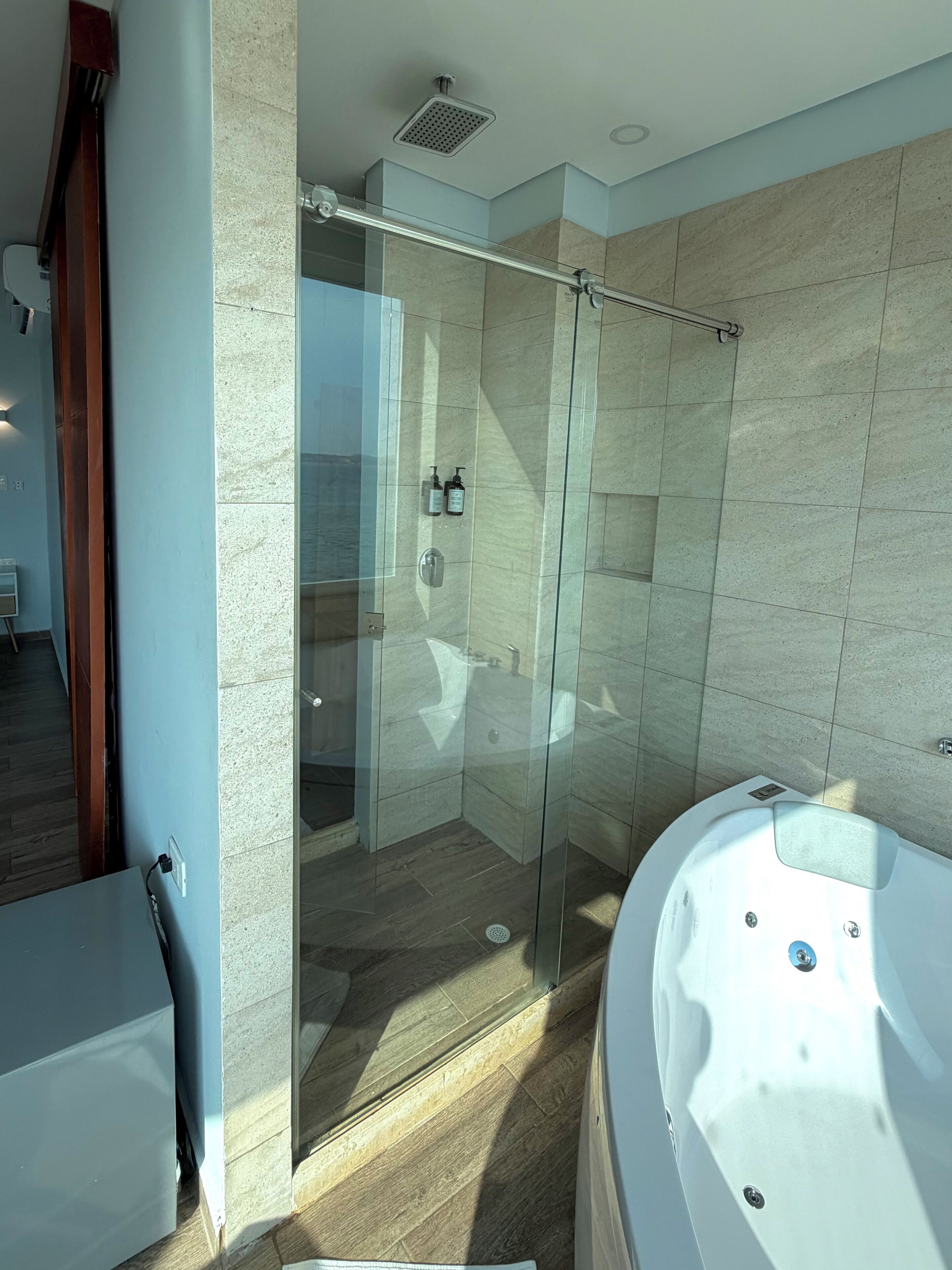 Egy modern fürőszoba üveg válaszfallal ellátott zuhanyzóval, fürdőkáddal és jól látható WC-vel.