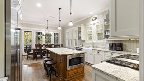 A modern kitchen with wooden cabinetry, a central island with stools, a built-in oven, and a gas stove.