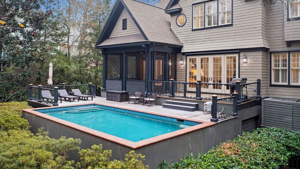 A house with a swimming pool, outdoor seating, and a covered patio area.
