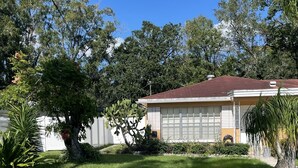 A residential house with a garage, surrounded by trees and a well-maintained lawn. - Private bedroom w/AC & Heating + Bathroom (Tampa)