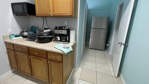 A compact kitchen with wooden cabinets, a microwave, a coffee maker, and a refrigerator. - Private bedroom w/AC & Heating + Bathroom (Tampa)