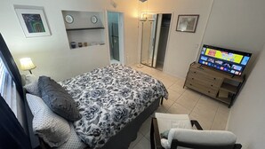 A bedroom with a bed, a chair, a TV, and a ceiling fan. - Private bedroom w/AC & Heating + Bathroom (Tampa)