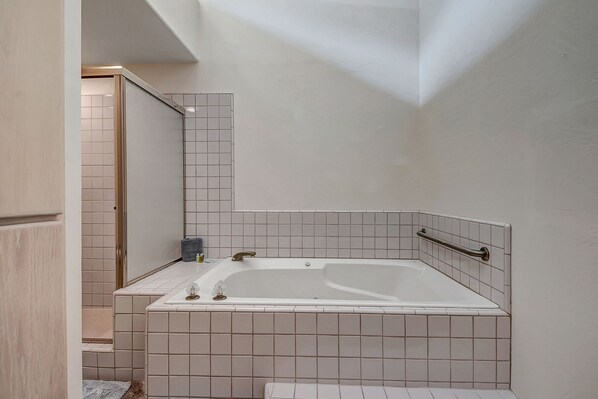Ein modernes Badezimmer mit freistehender Badewanne, gefliesten Wänden und einer Handstange.