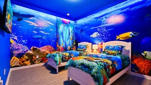 Ein Schlafzimmer mit Aquariumwand, zwei Betten und einem Nachttisch mit Lampe.