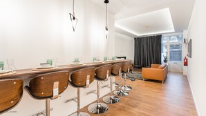 A modern dining area with a long wooden table, bar stools, and a sofa. - GuestReady - Uptown suites 1 (Porto)