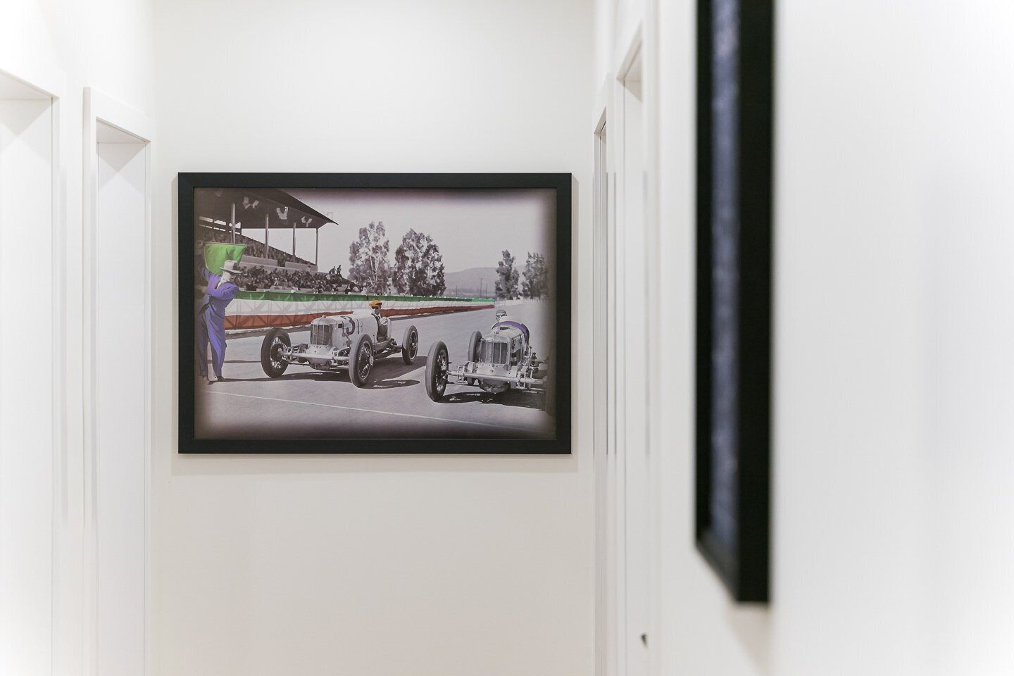 A framed photograph of a vintage racing car on a track with a person in a purple suit and hat.