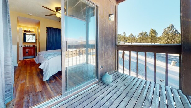 A room with a bed, a bathroom, and a balcony with a view of trees. - Walk to Lifts | Views | Fireplace | Bella Vista E1 (Angel Fire)