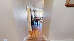 A narrow hallway with wooden flooring leading to a dining area with a table and chairs. - Walk to Lifts | Views | Fireplace | Bella Vista E1 (Angel Fire)