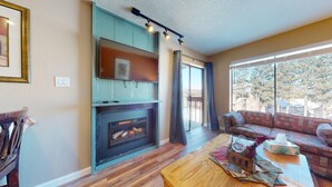 A living room with a fireplace, a sofa, and a coffee table. - Walk to Lifts | Views | Fireplace | Bella Vista E1 (Angel Fire)