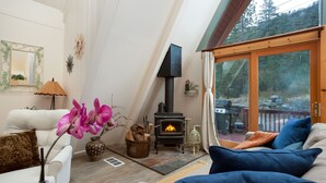 A cozy living room with a fireplace, a sofa, and a view of the outdoors.