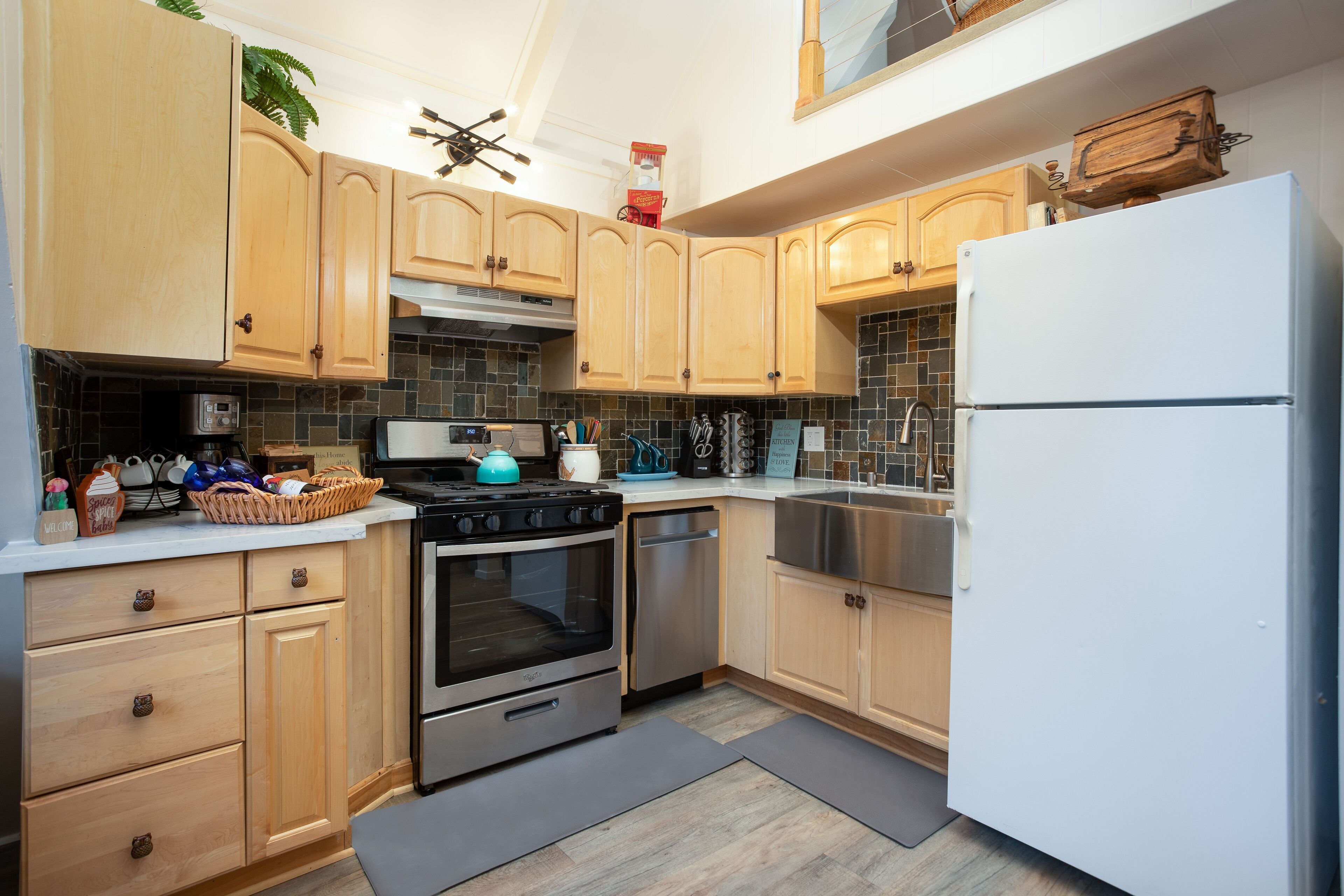 Een moderne keuken met houten kastjes, roestvrijstalen apparatuur en een betegelde achterwand.