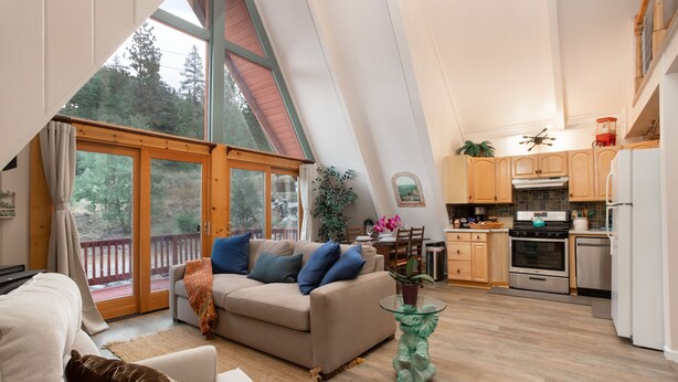 A modern interior with a living area, kitchen, and large windows overlooking a deck.