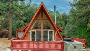 A cabin with a triangular roof, large windows, and a red deck.