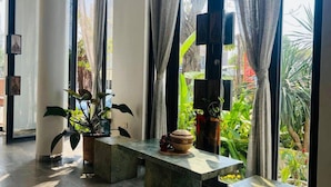 A room with a large window, a stone bench, and potted plants. - UTEY HOTEL (Siem Reap)