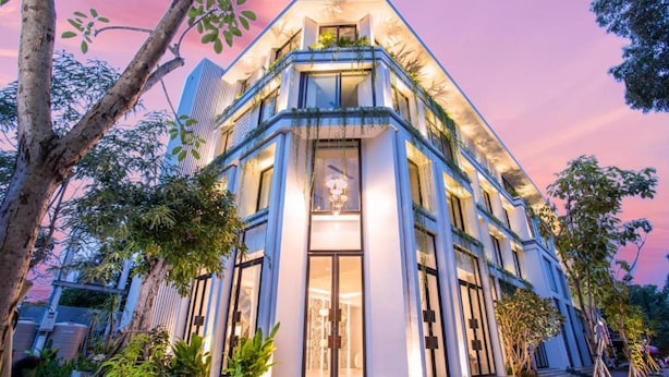 A modern building with a prominent entrance, large windows, and a balcony with plants. - UTEY HOTEL (Siem Reap)