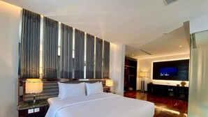 A modern hotel room with a large bed, a television, and a decorative wall panel. - UTEY HOTEL (Siem Reap)
