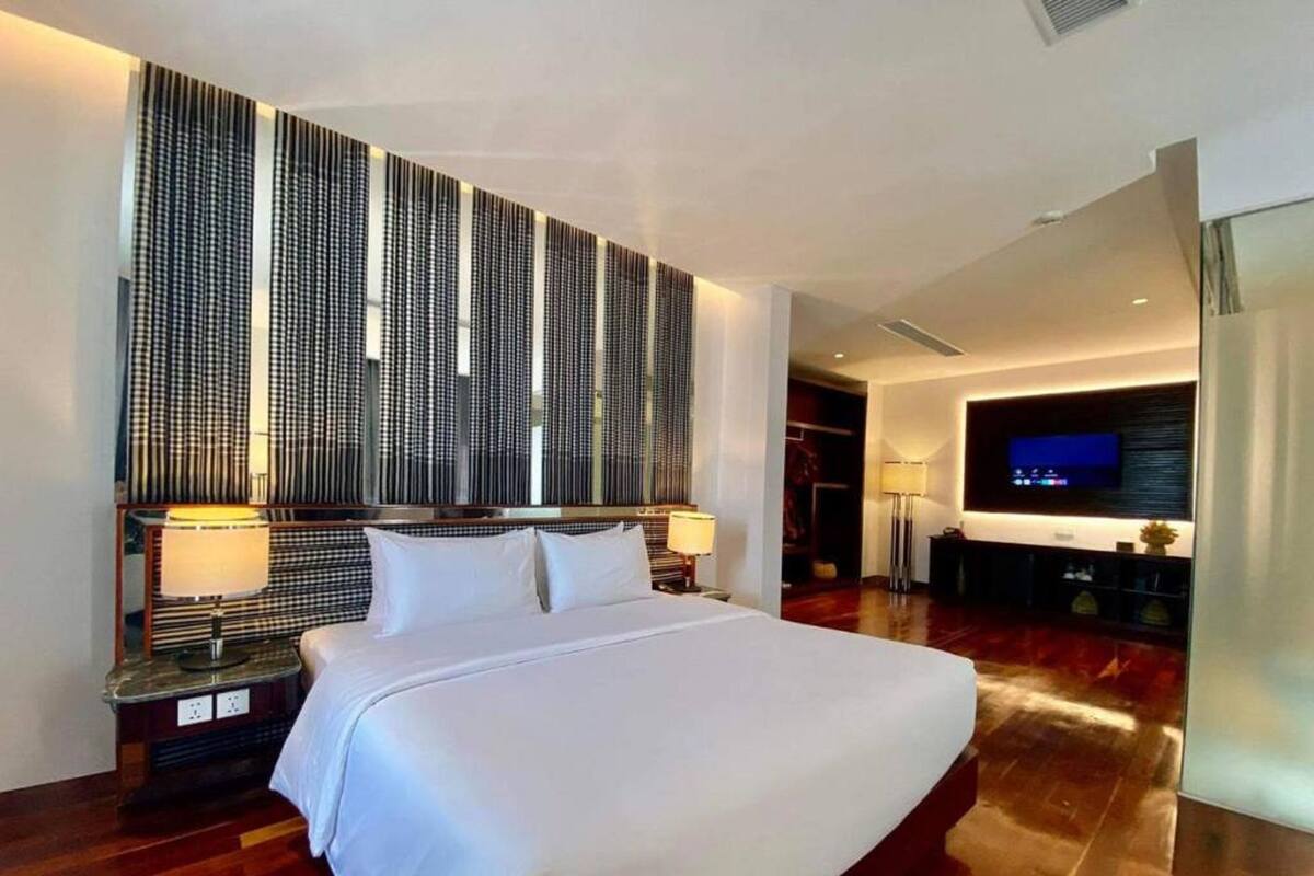 Una habitación de hotel moderna con una cama grande, un televisor y un panel decorativo en la pared.