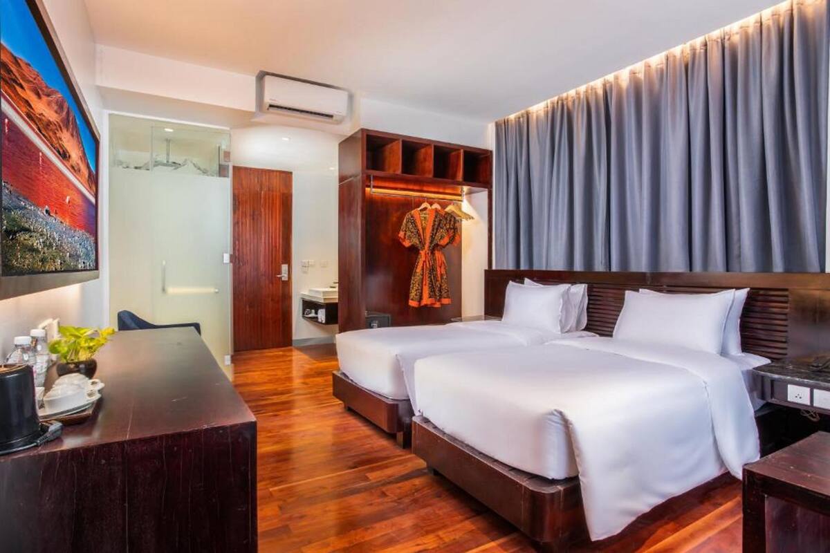 Habitación de hotel con dos camas, un escritorio, un armario y un cuadro grande en la pared.