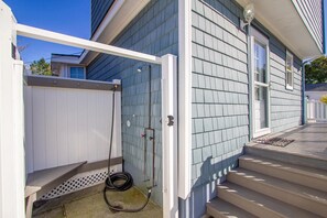 A residential building with a covered outdoor area, a hose, and a white fence.