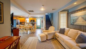 A spacious living area with a sofa, a dining table, and a kitchen in the background.