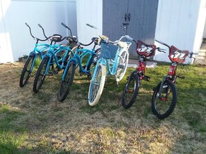 A row of bicycles parked on a grassy area in front of a building.