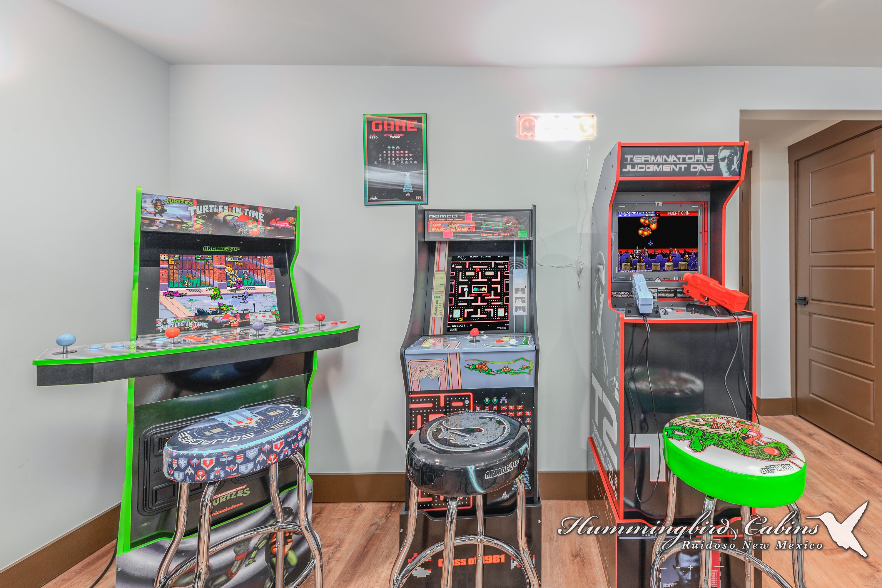 Arcade machines, a green stool, and a door in a room.