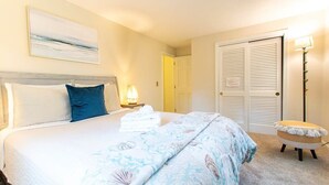 Una habitación de hotel con una cama, una lámpara de noche, una silla y una puerta.