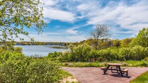 Una mesa de picnic y un banco en un sendero de ladrillo junto a un lago.