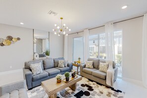 Un salon moderne avec deux canapés, une table basse et un lustre.