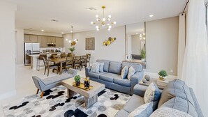Una sala moderna con sofá, mesa de centro y comedor con sillas y mesa.
