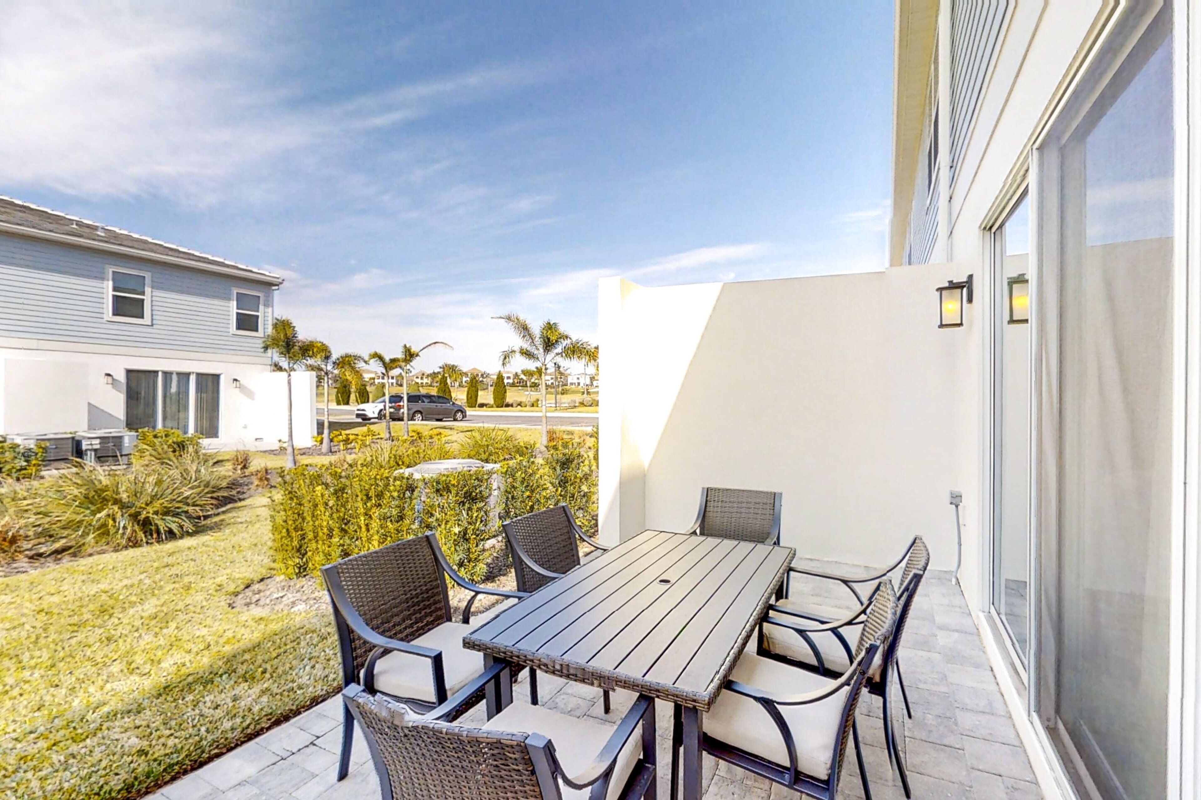 Een terras buiten met een tafel en stoelen, uitzicht op een woonwijk en een gebouw met een groot raam.