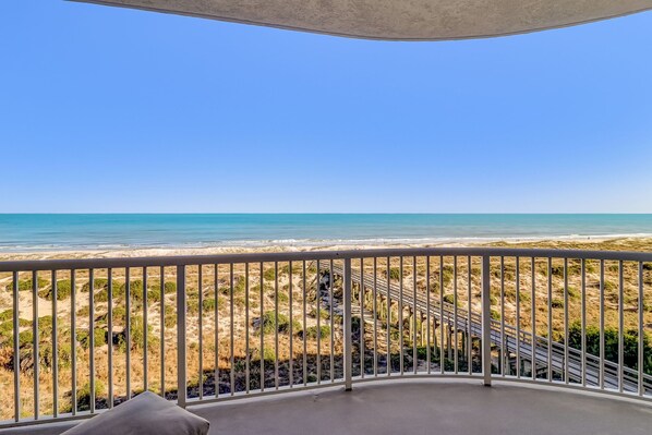 A balcony with a view of the beach and ocean.