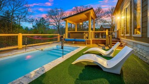A swimming pool with a sunken hot tub, lounge chairs, and a covered seating area. - Charming Creekside Escape: Pool, Putt-Putt, Game Room & Pet Friendly (Broken Bow)