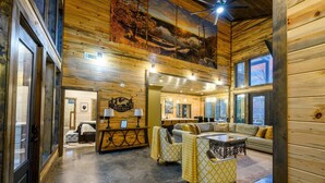 A spacious wooden interior with a large sofa, two armchairs, and a dining table. - Charming Creekside Escape: Pool, Putt-Putt, Game Room & Pet Friendly (Broken Bow)